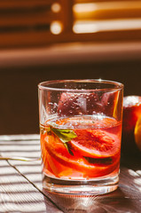 Refreshing blood orange water or infused water in a glass on a wooden background.