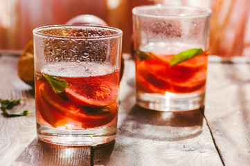 Refreshing blood orange water or infused water in a glass on a wooden background.