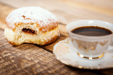 cup of delicious and fragrant coffee with a tasty donut on a wooden table