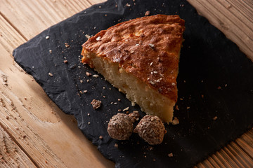 A piece of apple pie with grated chocolate near chocolate truffle candies. Selective focus and small depth of field.