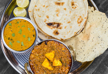 Indian Traditional Thali Food Kadai Paneer Served With Dal Makhani, Tandoori Roti or Papad on Vintage Wooden Background