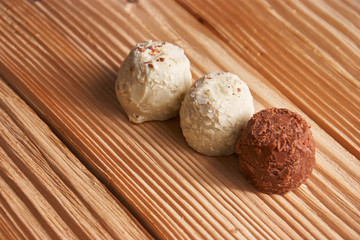Macro. White and milk chocolate candies on a light wooden background