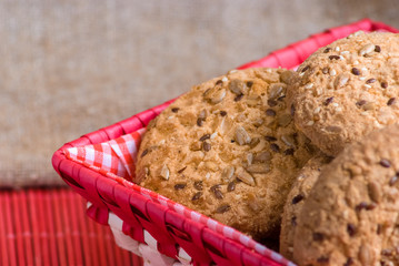 homemade oat cookies with sunflower seeds in and near red checkered basket on black wooden table