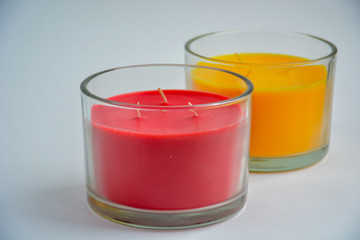 two candles isolated (red and yellow) in transparent glasses.in the foreground is a red