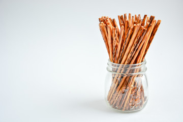 crispy crackers in the form of sticks in a transparent jar on a light background