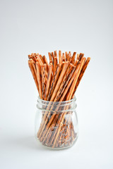 crispy crackers in the form of sticks in a transparent jar on a light background