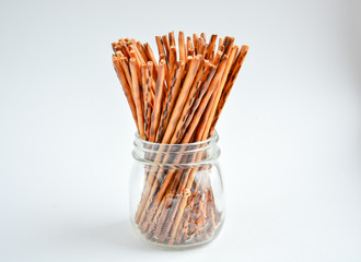 crispy crackers in the form of sticks in a transparent jar on a light background
