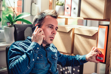 Businessman sitting at the desk talking on the phone and reaching for ring board