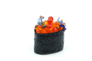 Miniature people : businessman sitting with Salmon egg on sushi nigiri roll , Food business concept.