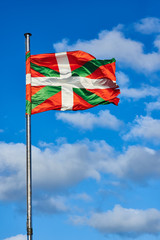 Ikurrina, Basque Country flag waving on a blue sky.