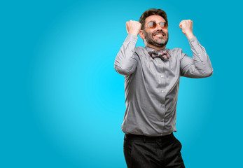 Middle age man, with beard and bow tie happy and excited celebrating victory expressing big success, power, energy and positive emotions. Celebrates new job joyful