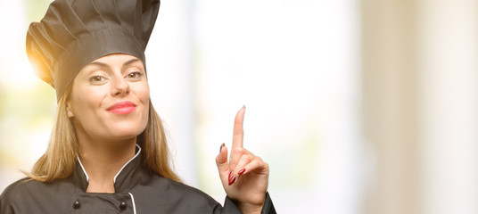 Young cook woman happy and surprised cheering expressing wow gesture pointing up