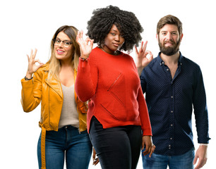 Group of three young men and women doing ok sign with hand, approve gesture