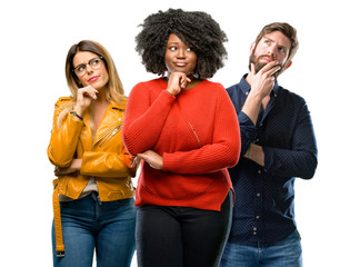 Group of three young men and women thinking and looking up expressing doubt and wonder