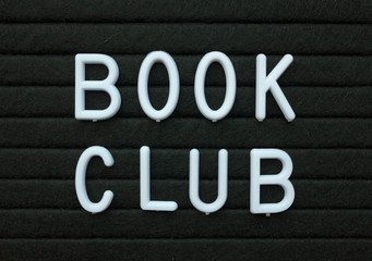 The words Book Club in white plastic letters on a black letter board as a reminder of an event for avid readers and book worms