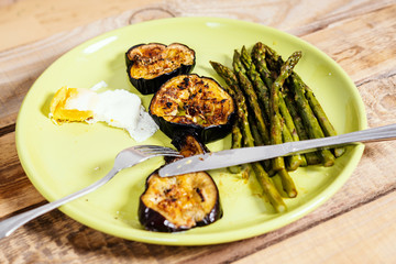 delicious dinner of asparagus fried eggs and courgette on a green plate on a wooden table