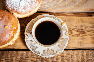 cup of delicious and fragrant coffee with a tasty donuts on a wooden table