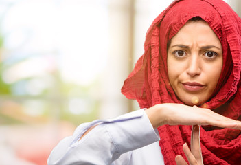 Fototapeta premium Young arab woman wearing hijab serious making a time out gesture with hands