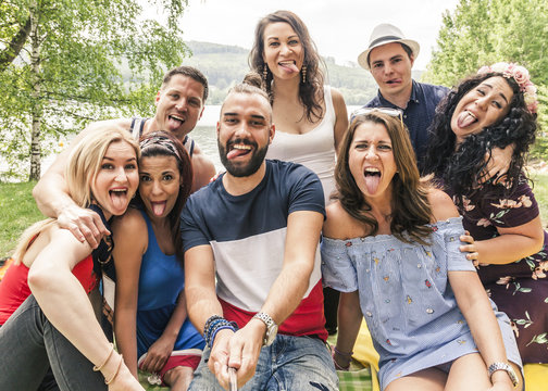 Acht Freunde machen ein Selfie Foto. Verr&uuml;ckte Jugendliche strecken ihre Zungen raus.