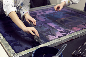 Textile designers screen printing pattern in workshop