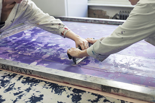 Textile designers screen printing pattern in workshop