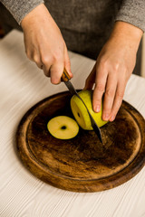 Woman cuts green apple on board close
