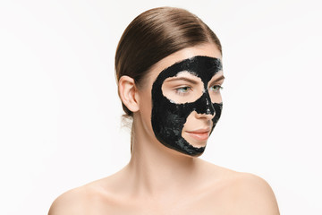 Young beautiful woman applying a mask for the face of the therapeutic black mud. Spa treatment