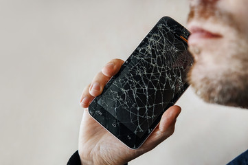 The guy is talking on the phone with a broken screen.