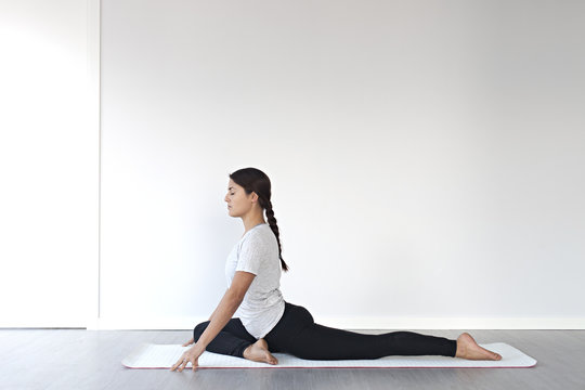 Young girl stretching in pigeon yoga pose