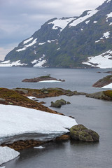 Mountain lake on the Norwegian Scenic Route Ryfylke in overcast cool day, Norway. Snow in mountains does not thaw even in the summer.