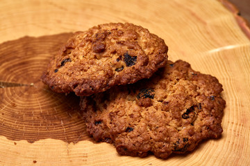 Couple of chocolate biscuits on a round wood log over rustic wooden background, close-up, selective focus.