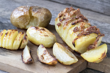 Baked potatoes of different kinds located on a wooden background in rustic style close-up