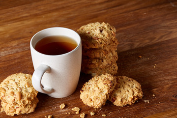 White porcelain mug of tea and sweet cookies on wooden background, top view, selective focus