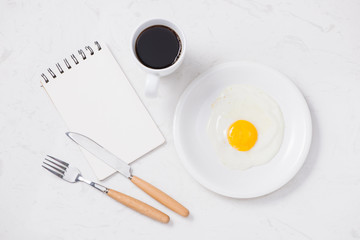 Top view of white dish with fried egg on white background.
