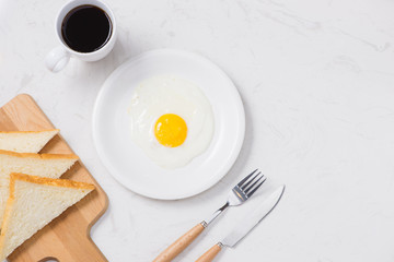 Top view of white dish with fried egg on white background.