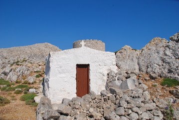 A small chapel and old stone windmill on the high plateau of the Greek island of Halki.