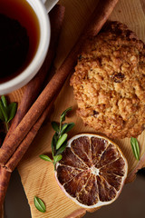 Christmas concept with a cup of hot tea, cookies and decorations on a log over wooden background, selective focus