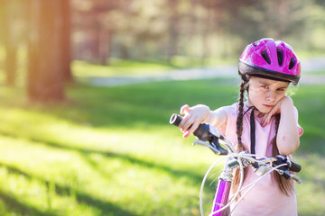 child in protective helmet learning to ride a bike. girl is sad and angry. Active leisure for...