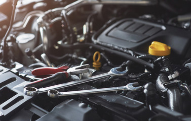 Naklejka premium Mechanik sprawdza i naprawia zepsuty samochód w warsztacie samochodowym
