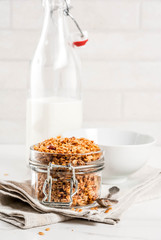 Homemade granola from mix of cereals (barley, oat, rye, bran) with dry fruits, nuts, with fresh organic milk on white marble background