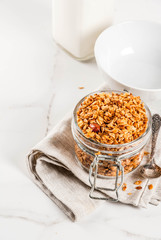 Homemade granola from mix of cereals (barley, oat, rye, bran) with dry fruits, nuts, with fresh organic milk on white marble background