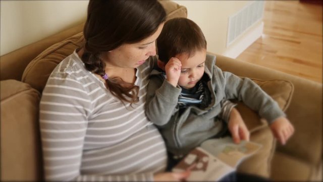 Pregnant mother reading a book with her toddler