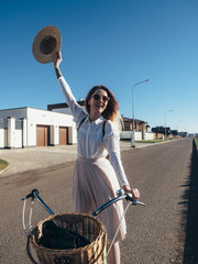 Plakat Pretty girl in hat and dress by cruiser bicycle in suburb