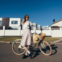 Plakat Pretty girl in hat and dress by cruiser bicycle in suburb