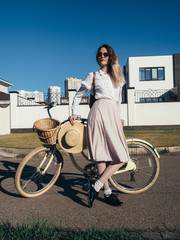 Naklejka na ściany i meble Pretty girl in hat and dress by cruiser bicycle in suburb