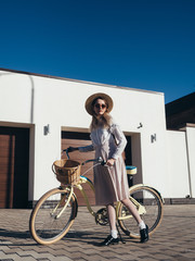 Plakat Pretty girl in hat and dress by cruiser bicycle in suburb