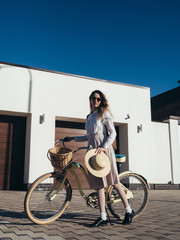 Plakat Pretty girl in hat and dress by cruiser bicycle in suburb