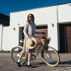Plakat Pretty girl in hat and dress by cruiser bicycle in suburb