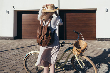 Plakat Pretty girl in hat and dress by cruiser bicycle in suburb