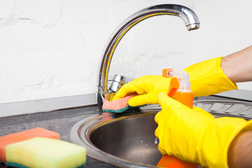 man in protective gloves is cleans the sink using a spray and a duster while cleaning house, close-up